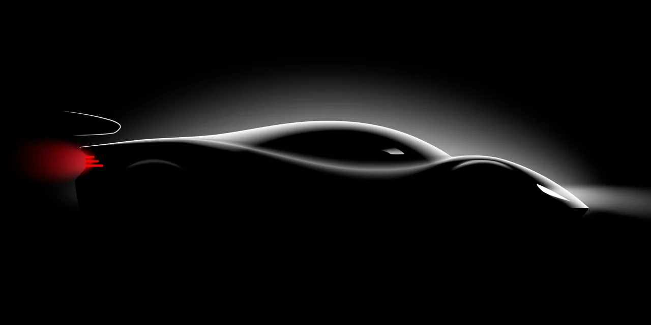 Silhouette of a low-slung race car lit from above in a dark studio, tail light glowing red